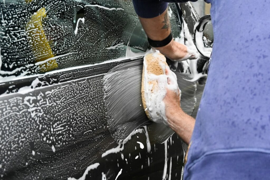 Owner-operator hand washing a vehicle at a customer home