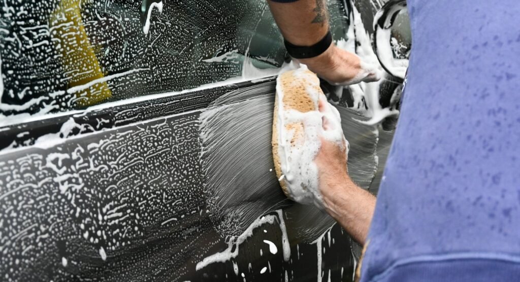 Detailer working on a vehicle in a driveway