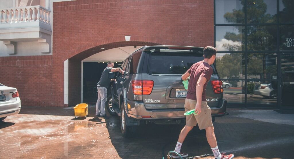 Detailer hand cleaning a silver SUV