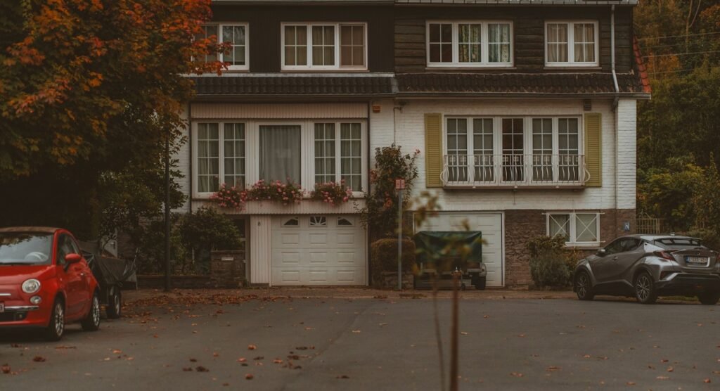 Two cars parked outside a house on an autumn street